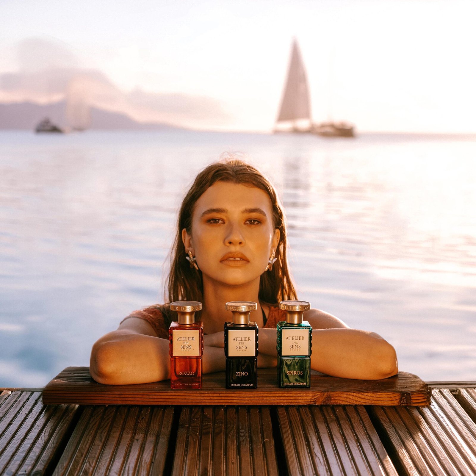 a woman sitting at a table with bottles of Atelier des Sens perfumes